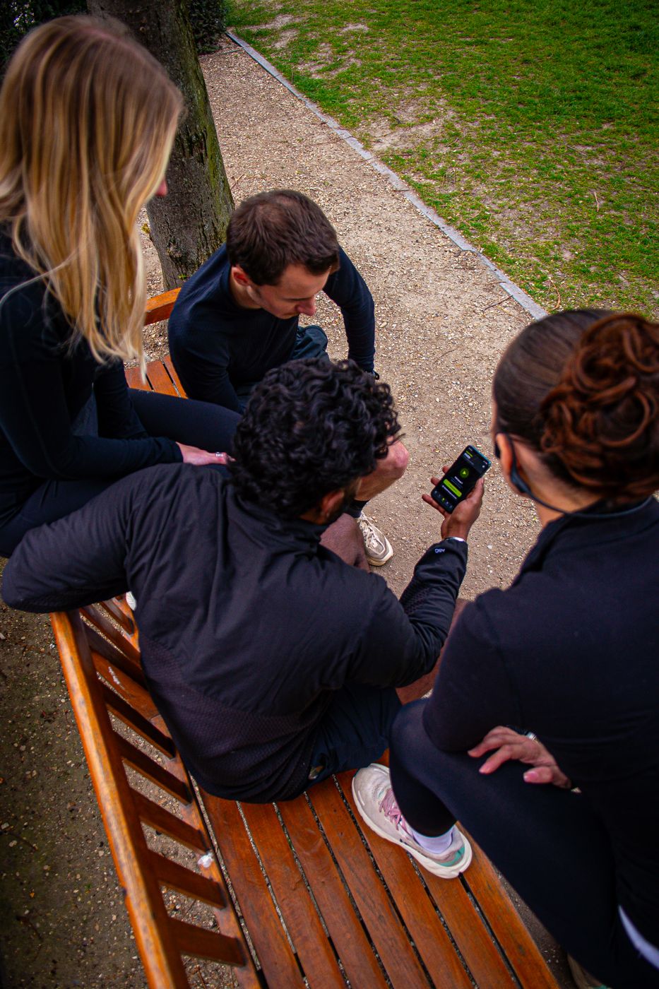 Un groupe d'amis rassemblé sur un banc autour de l'application.