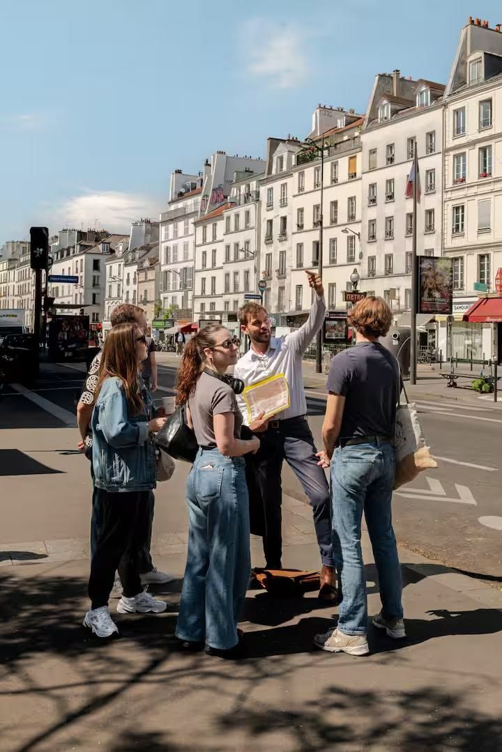 Un groupe s'oriente dans une rue de Paris, au pied des immeubles haussmanniens.